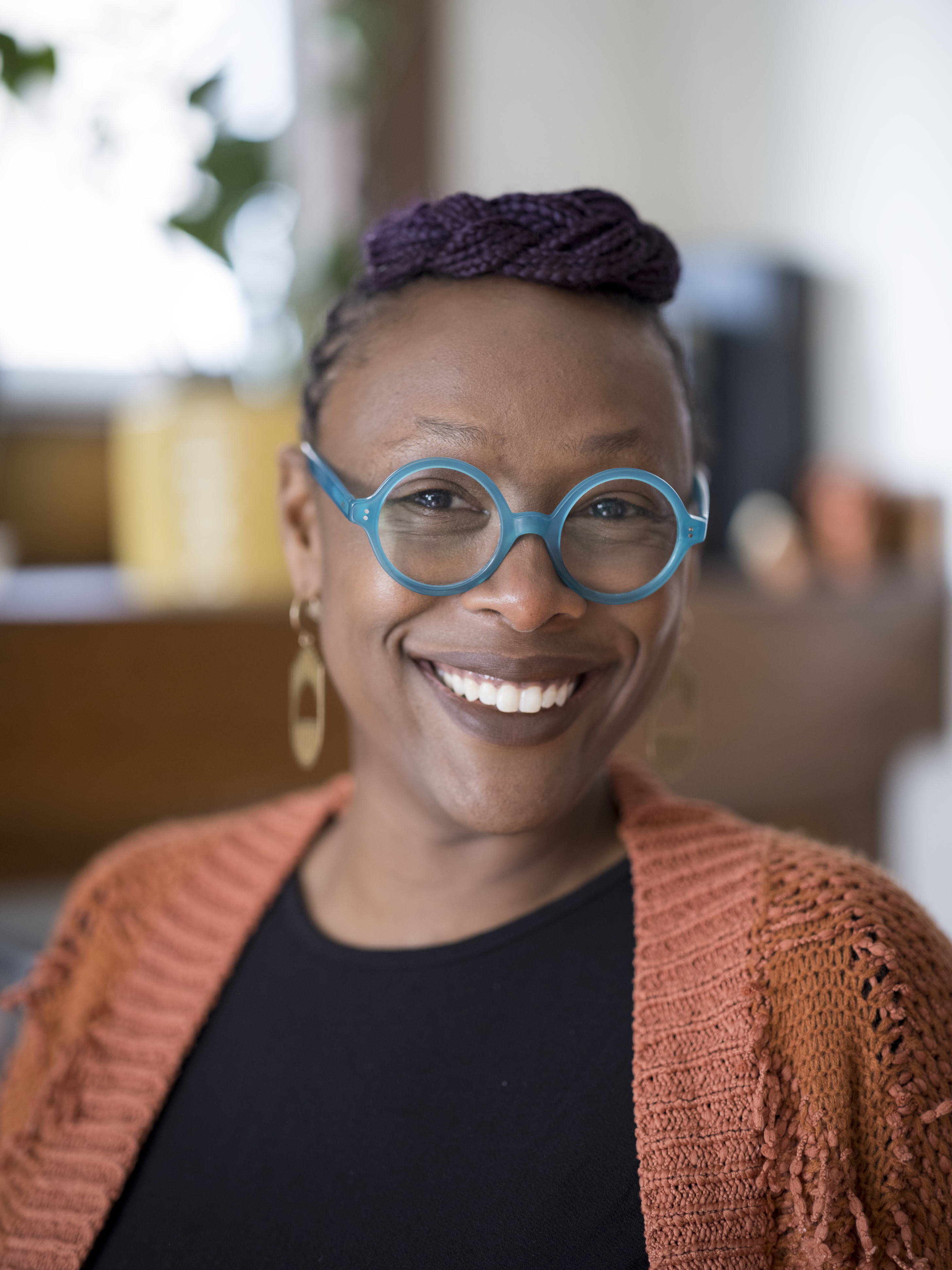 Woman smiling at camera wearing blue framed glasses