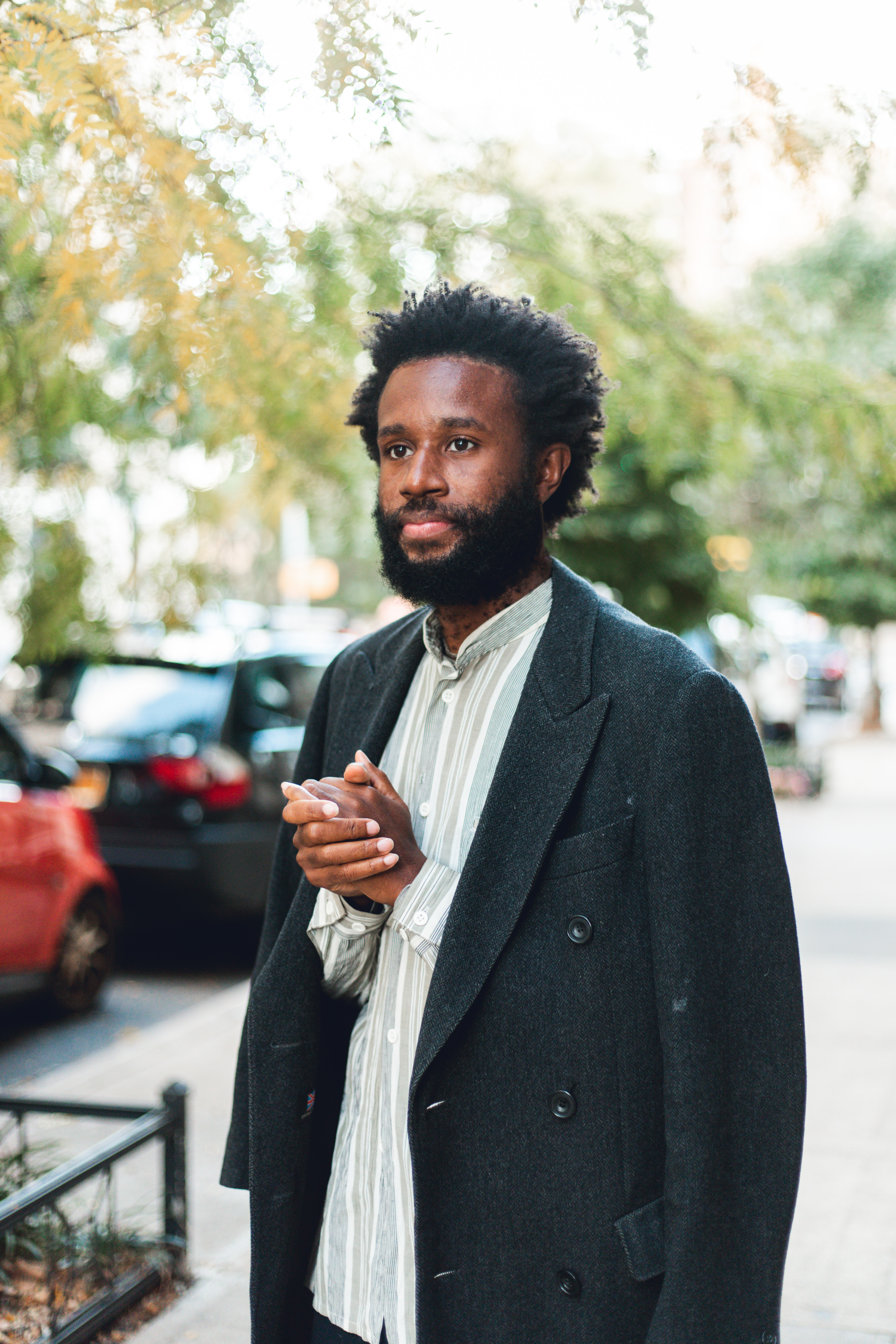 man standing on city sidewalk with hands clasped