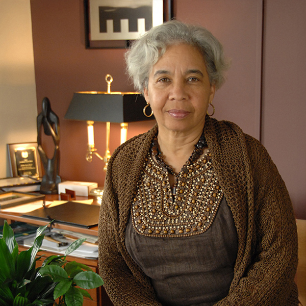 Woman dressed in brown subtly smiles at camera