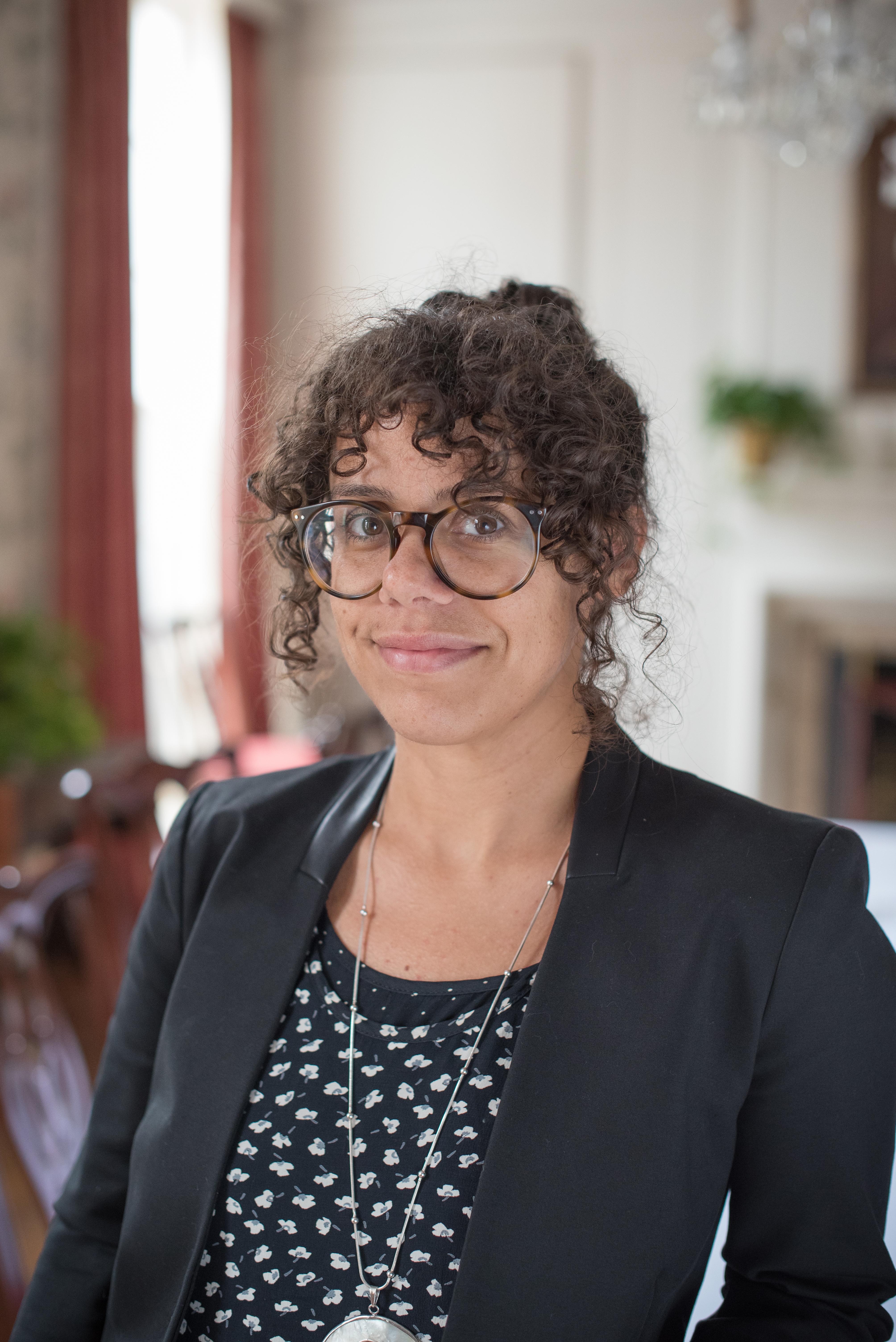 A woman wearing large glasses smiles at the camera