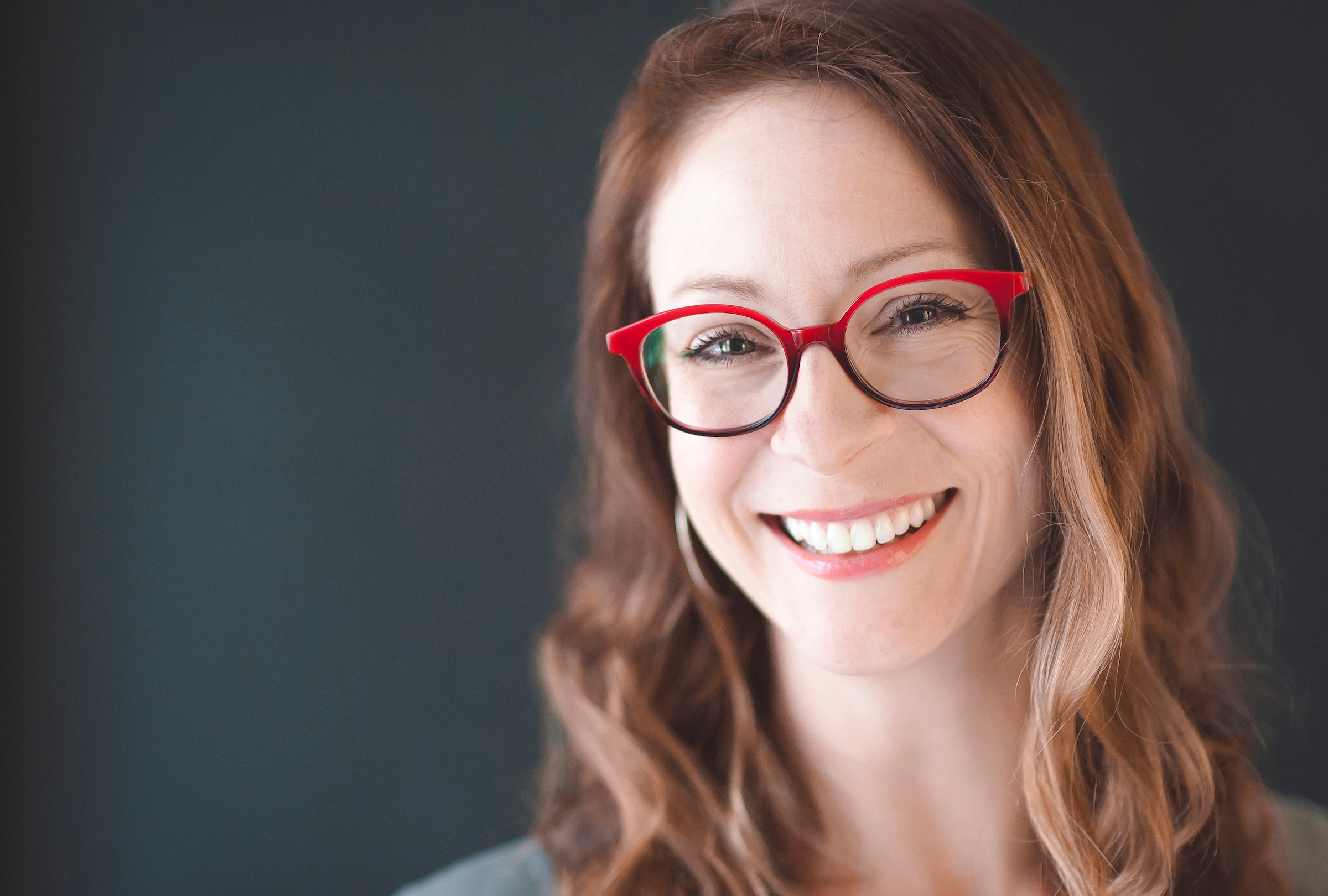 Close-up of smiling woman in red-framed glasses