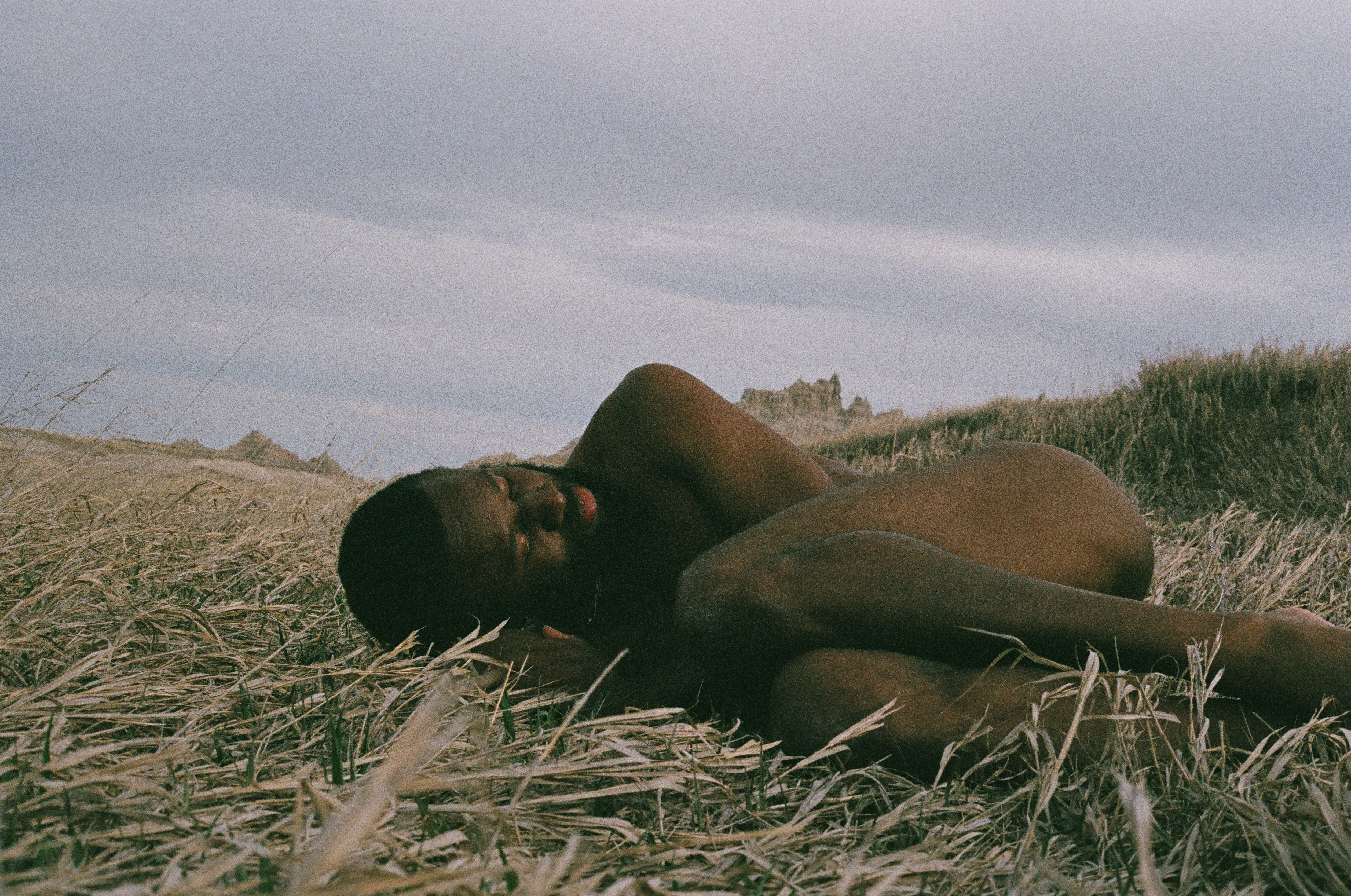 man in fetal position in a field