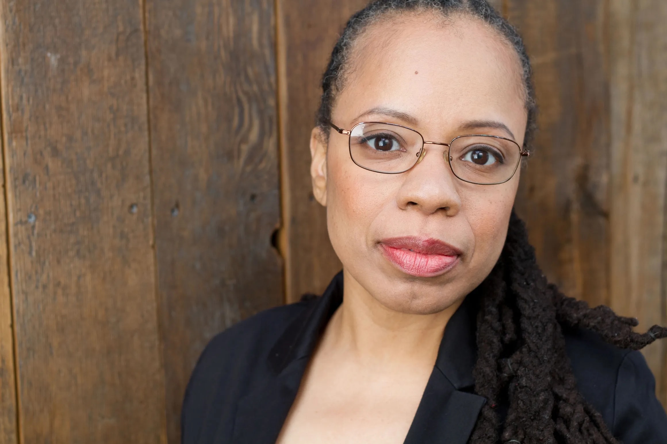 woman in glasses looks directly at camera