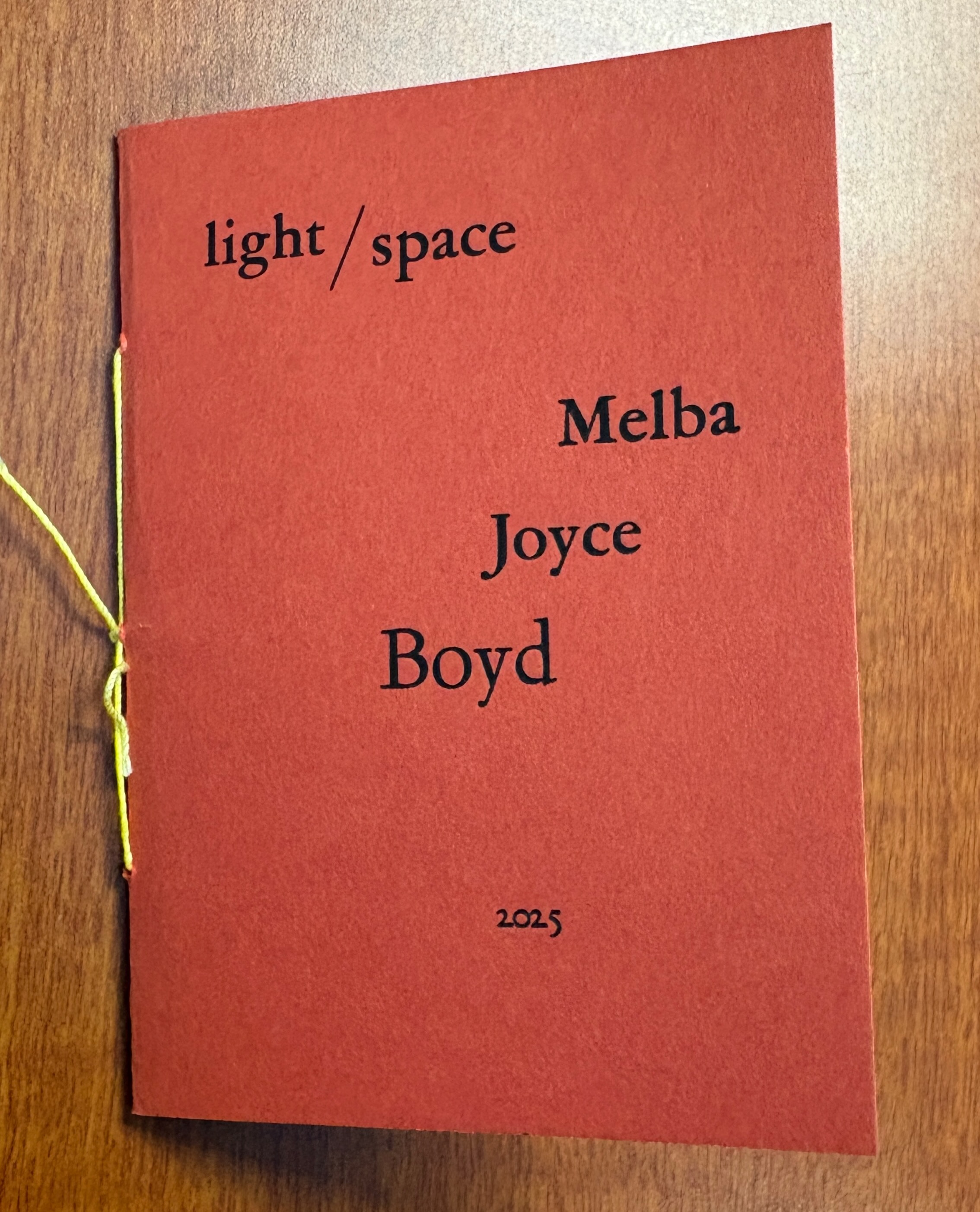 A red, hand-stitched booklet bearing the title "light/space" and Melba Joyce Boyd 2025